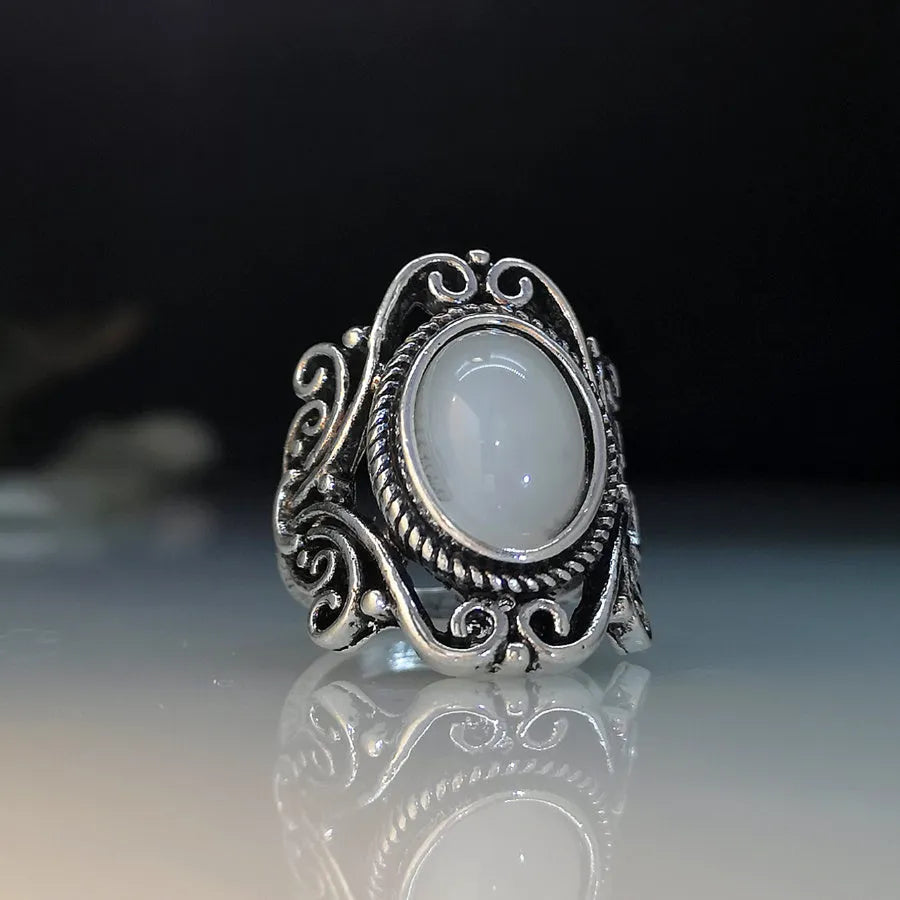 Vintage alloy ring with flower-shaped artificial moonstone gemstone on a neutral background showing side view