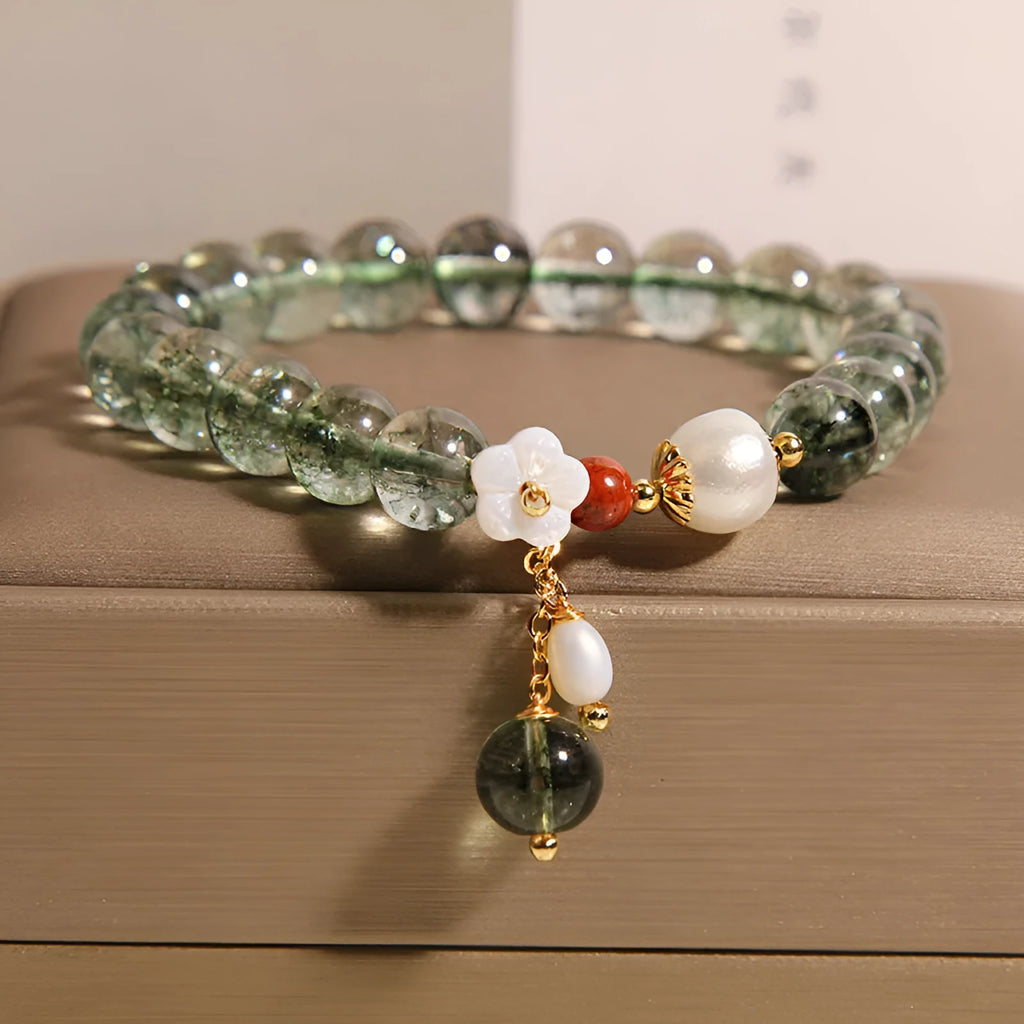 Green phantom quartz crystal bracelet with a silver shell flower charm on a model's wrist.