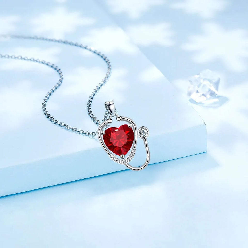 Women's fashion necklace with stethoscope, wings and cross design in red diamond colour