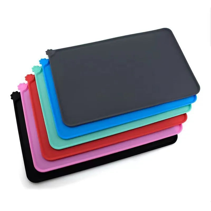 Silicone pet placemat under dog food and water bowls in a grey colour on a wooden floor.