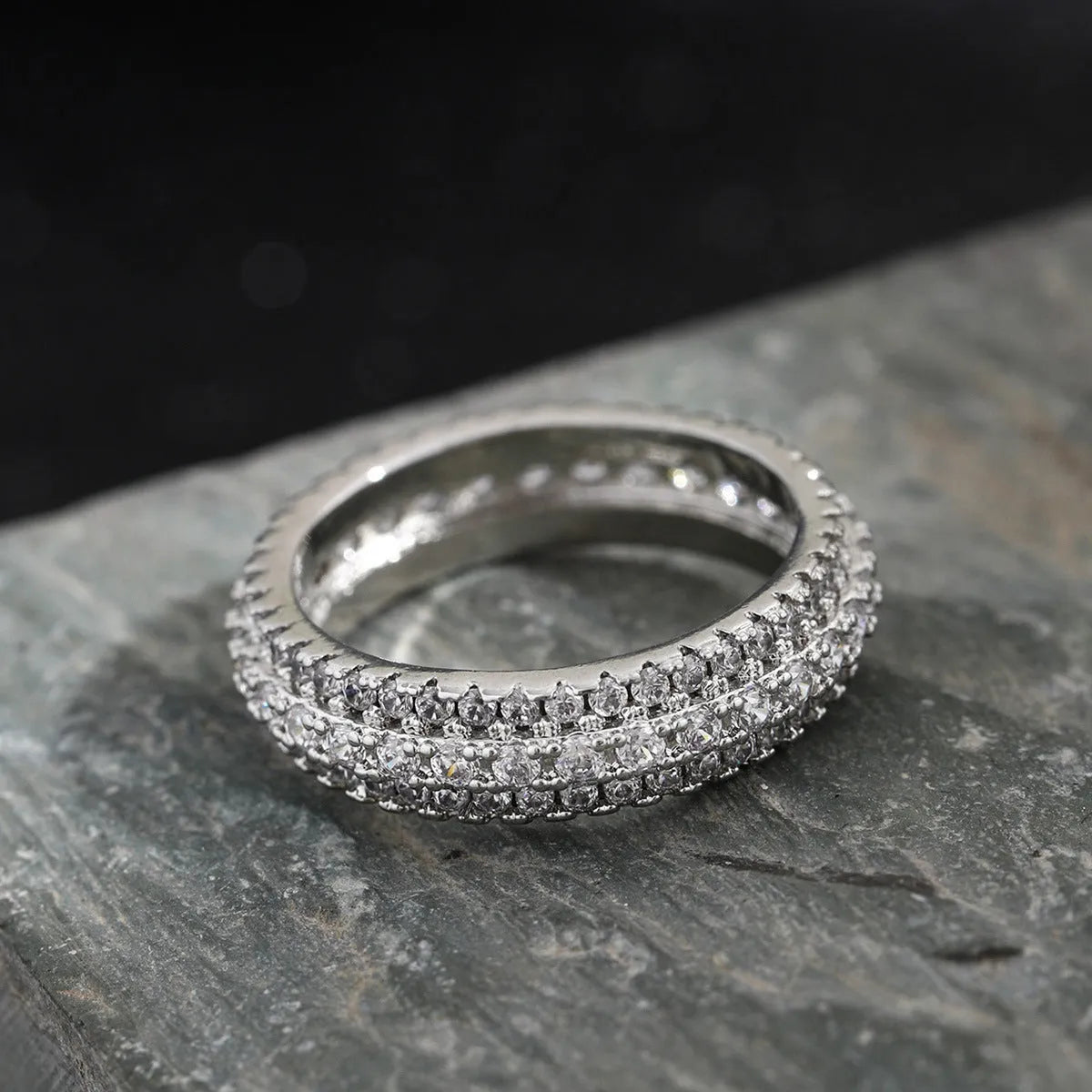 Geometric copper ring with triangular zircon inlay, shown in platinum, yellow gold and white-black finishes.