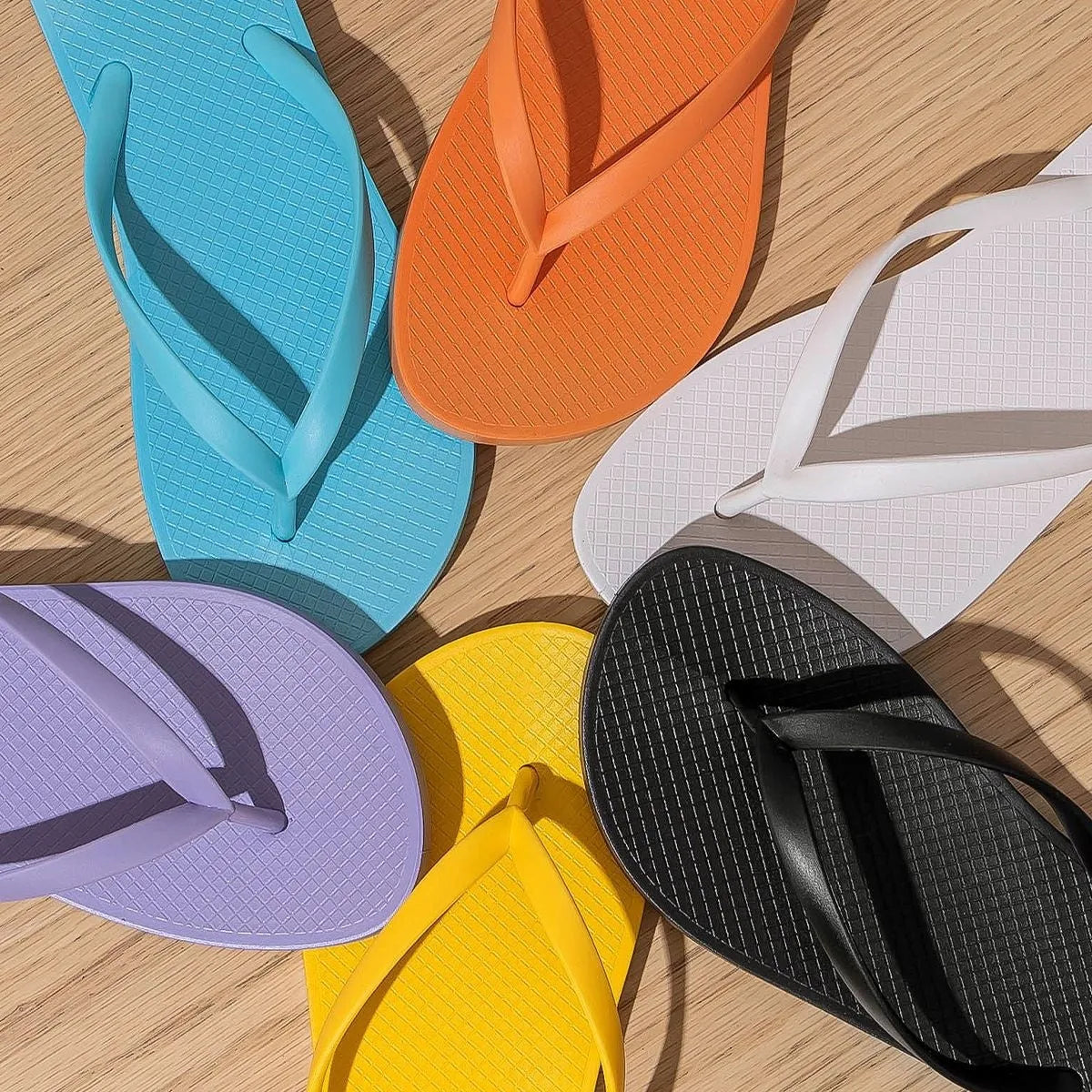 Foldable PVC beach slippers with hollow-out design and non-slip sole in black, purple and white colour options.