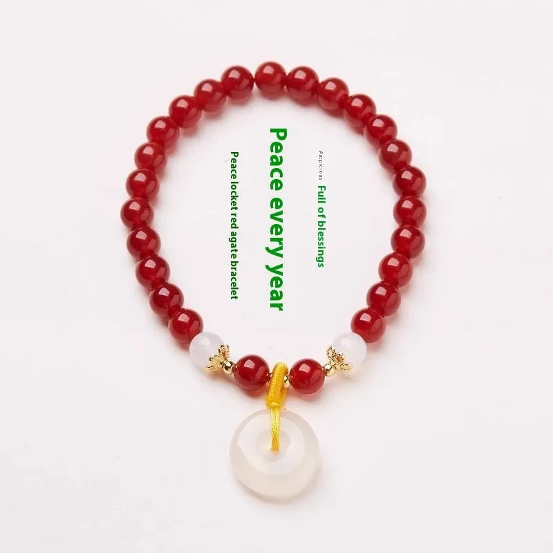 Handmade natural jade and red agate bracelet with silver safety buckle on wooden background
