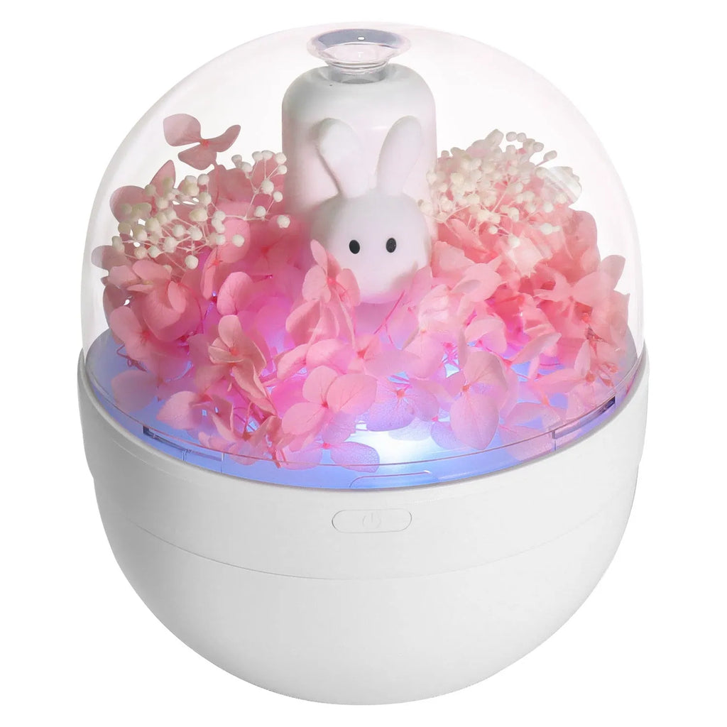Pink rabbit-shaped aromatherapy humidifier with preserved flower decoration on bedside table