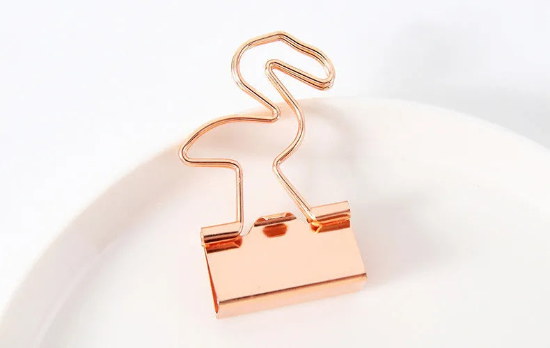 Gold metal decorative paper clip in a bow shape with a long tail design.