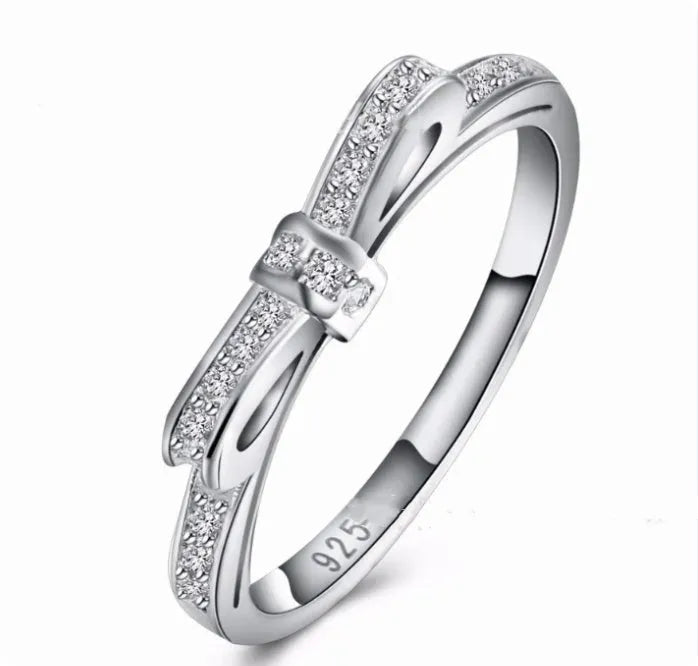 Silver-colour bow ring with zircon crystal details on a white background.