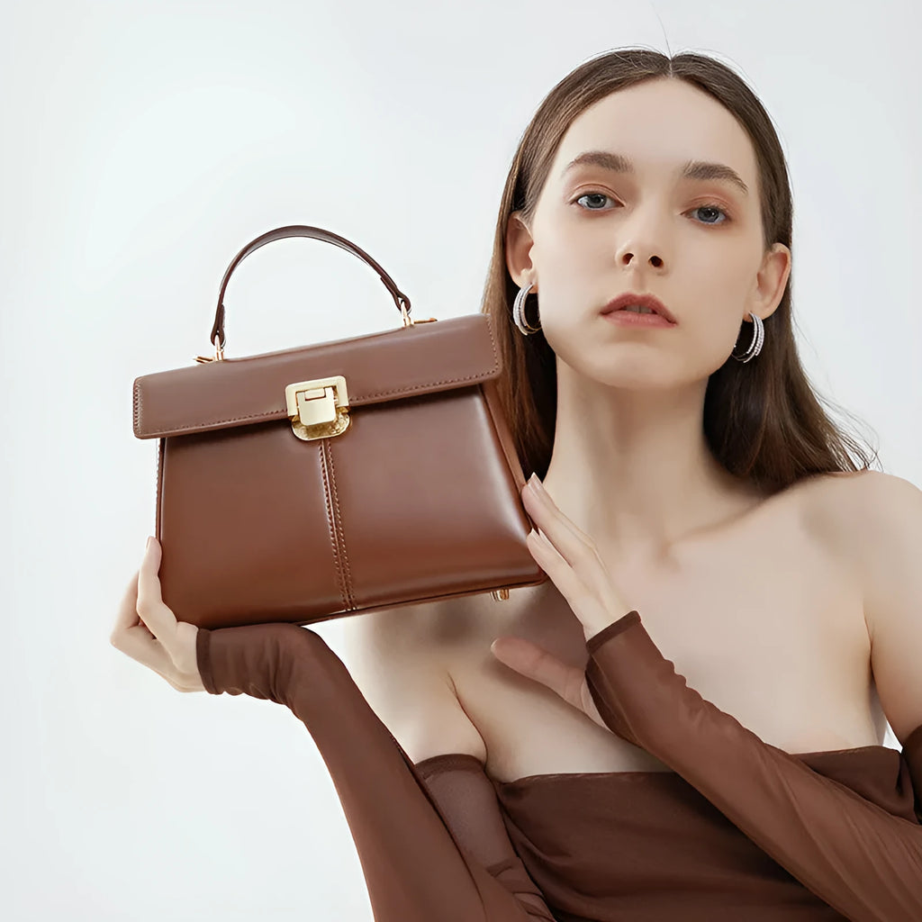 Women's black leather shoulder bag with clasp closure and adjustable strap showing interior organisation