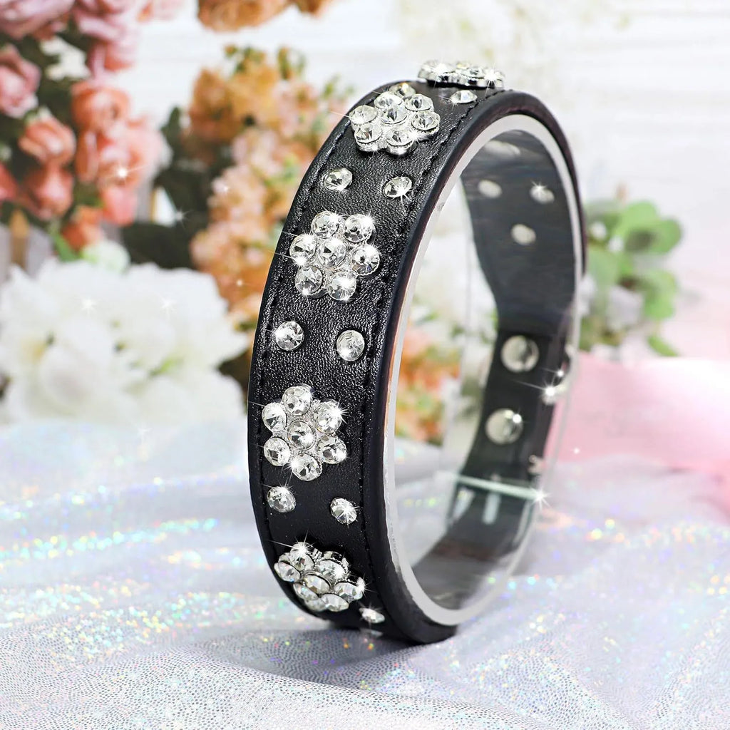 Black dog collar with shiny rhinestone flower pattern and metal D-ring on a soft PU leather strap.