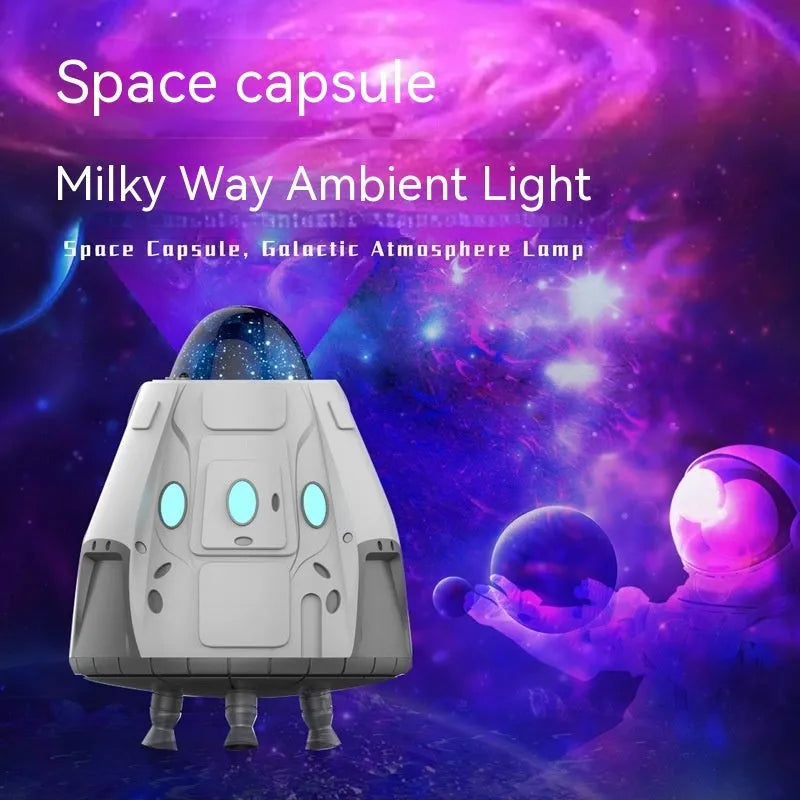White space capsule shaped Bluetooth Northern Lights ambience light with remote control on a dark surface.