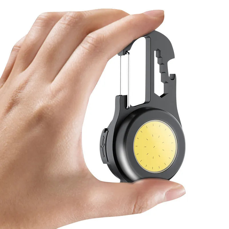 Black 6-in-1 multi-functional mini keychain lamp with COB light and magnetic base on metal surface