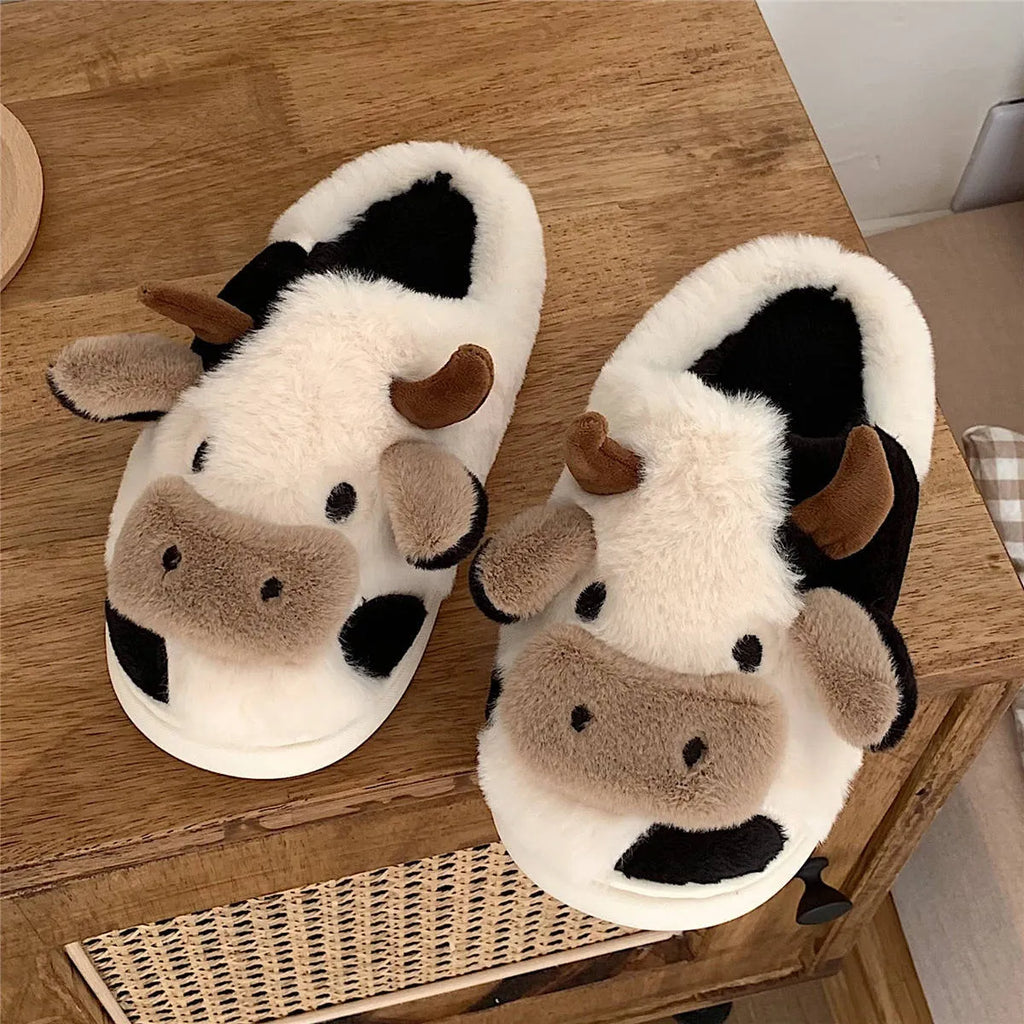 White cartoon cow slippers with plush faux fur and a textured non-slip sole.