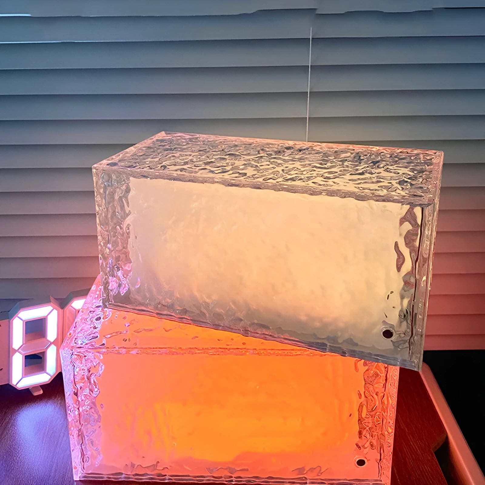 Small geometric acrylic night lamp glowing with multicoloured LED light on a table.