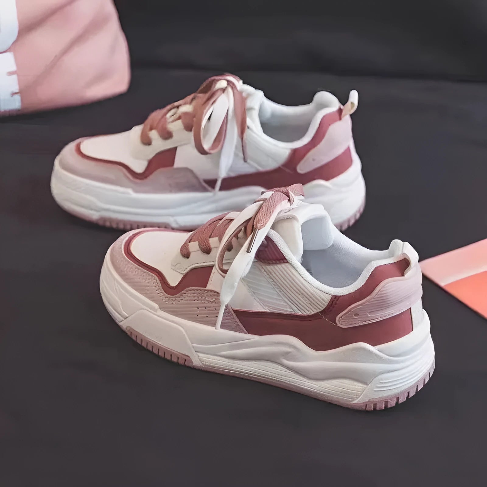Women's beige and pink low-top lace-up sneakers with a rubber sole on a white background.