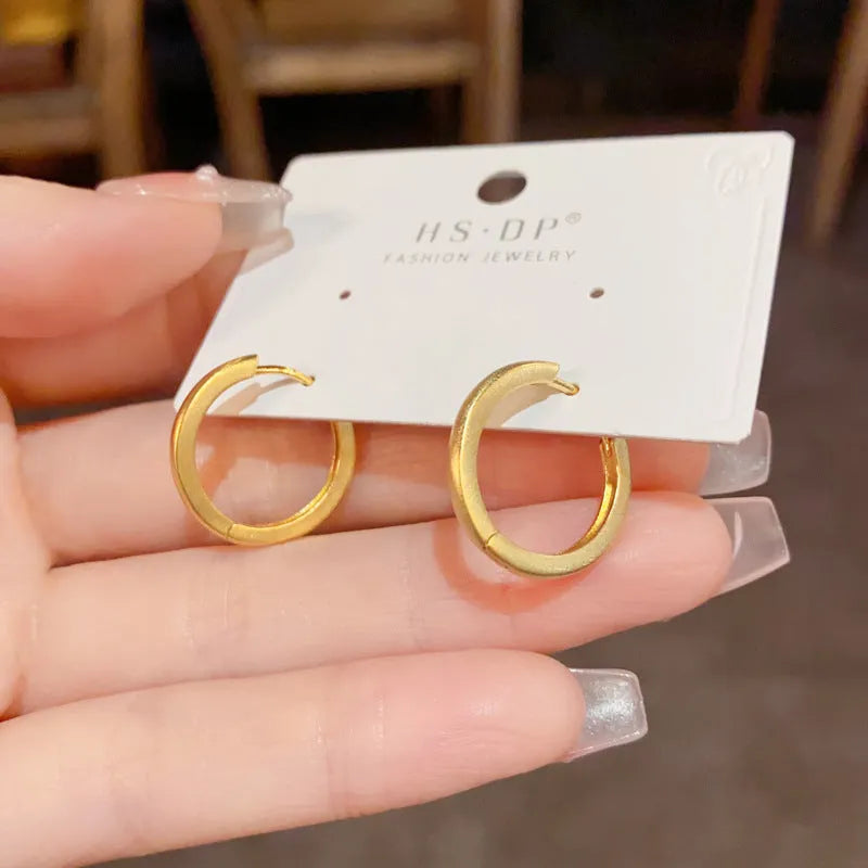 A pair of geometric circle ear clips for women in gold or silver finish.
