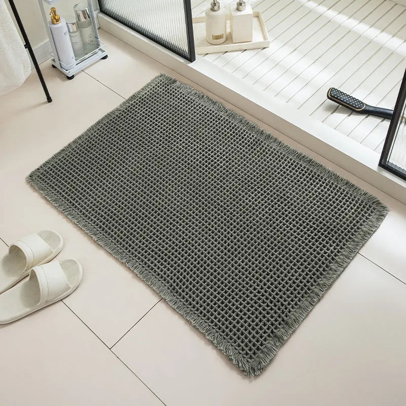 A square, checkered-pattern bathroom carpet in a choice of colours on a tiled floor.