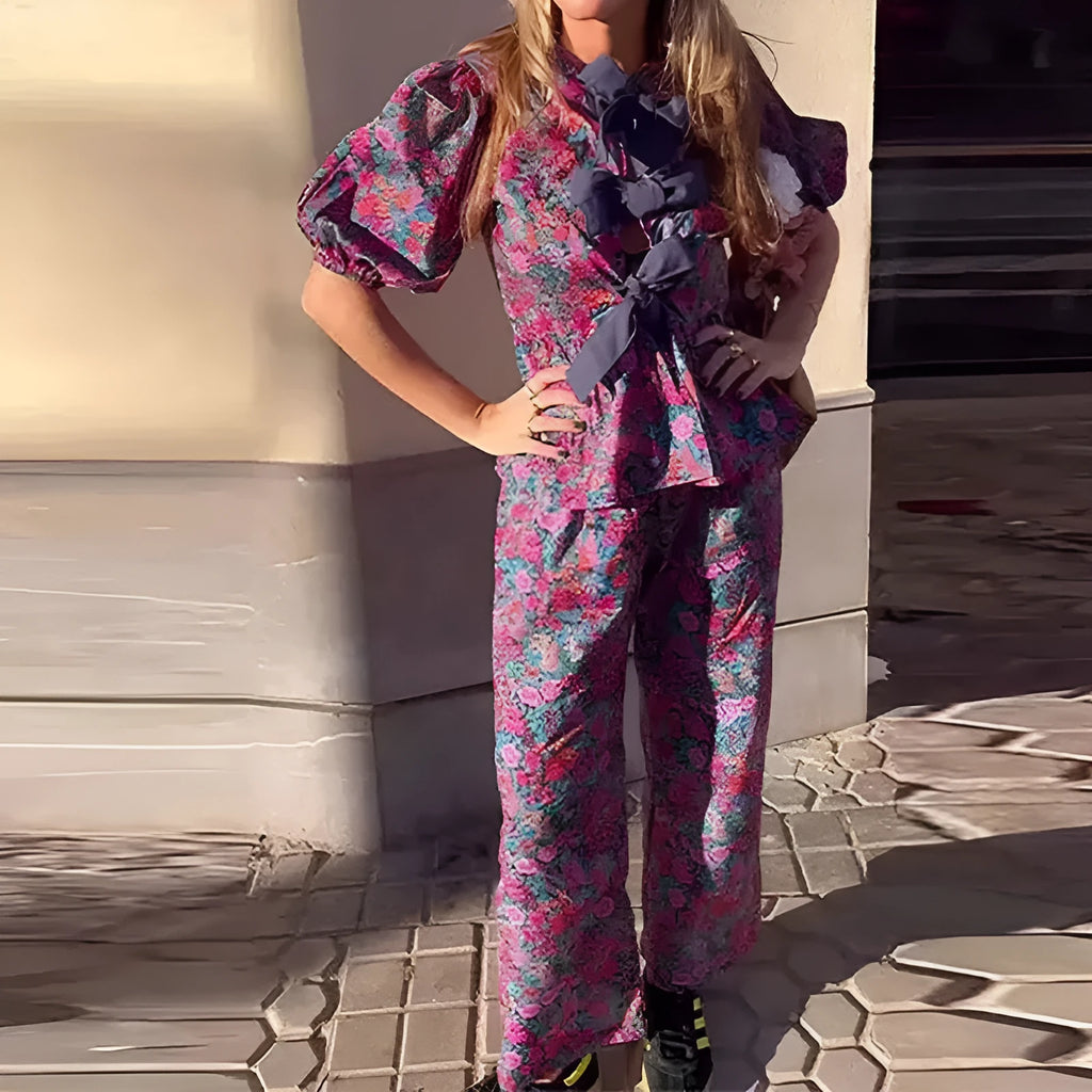 Women's floral print polyester trouser suit with puff sleeve blouse and matching trousers on a hanger.