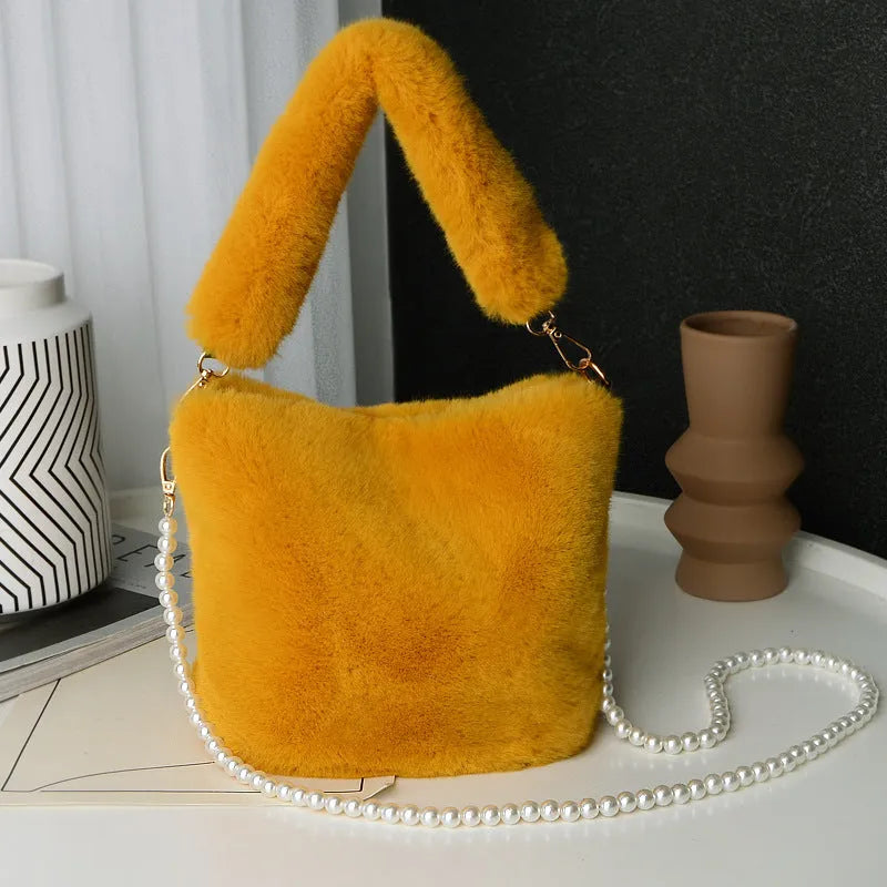 Plush bucket bag with gold-toned pearl chain on a beige background