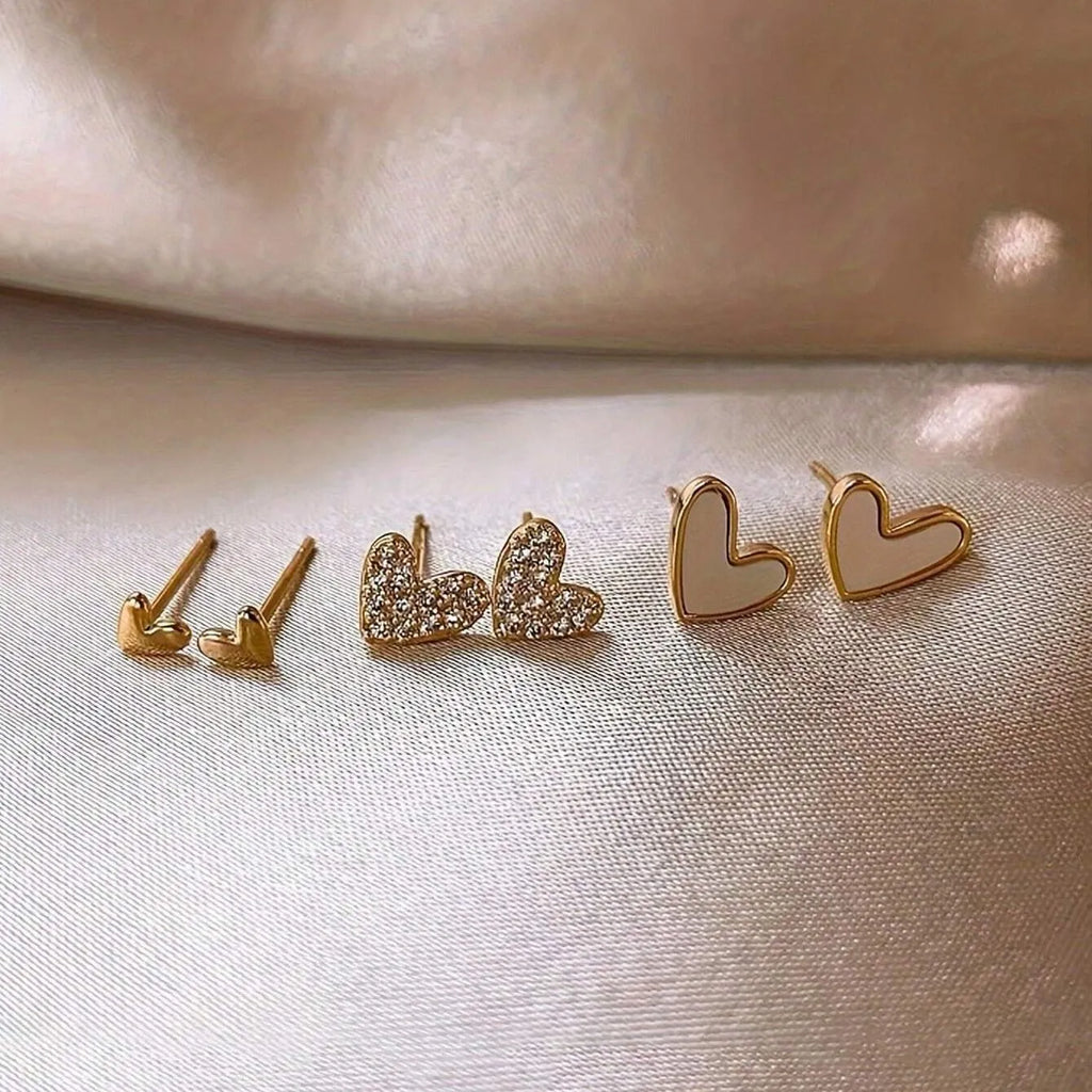 Set of three pairs of heart-shaped alloy earrings in gold, black, white, and pink colours.