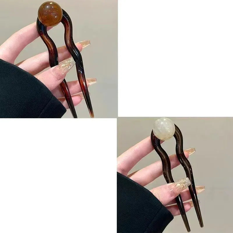 Acrylic U-shaped hair barrette with a small spherical decoration in a beige and caramel two-tone colour combination.