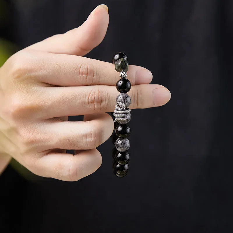 Men's black obsidian and sterling silver snake bracelet with retro design on a wrist.