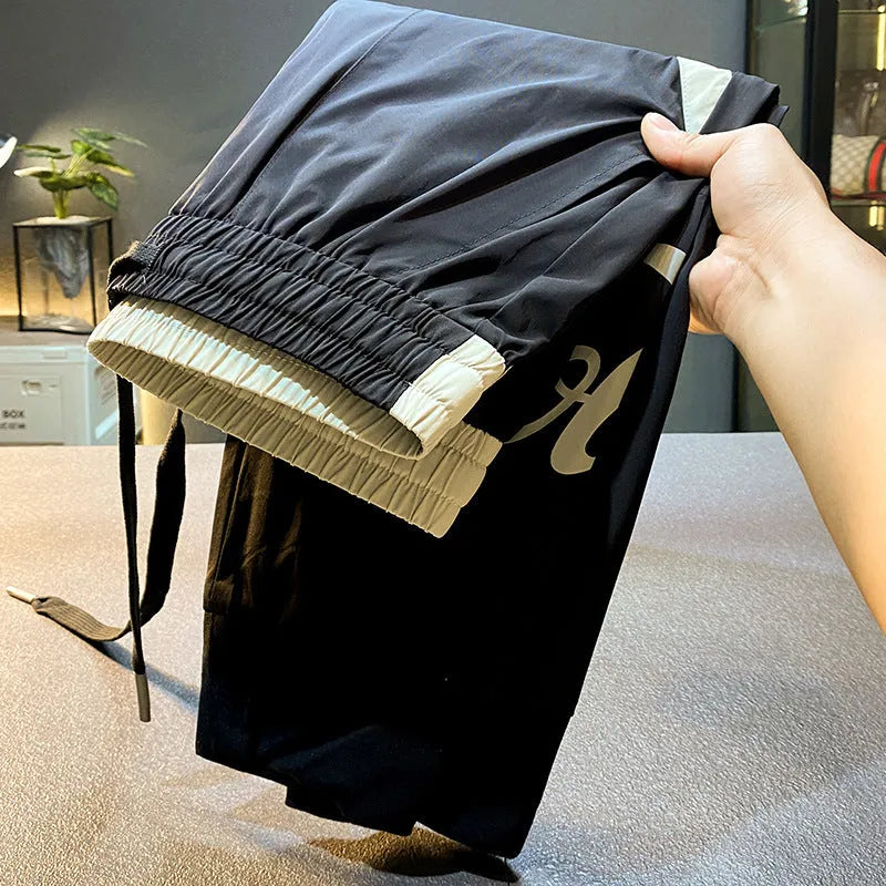Black men's casual cotton trousers with cropped legs and an ankle band on a solid background.