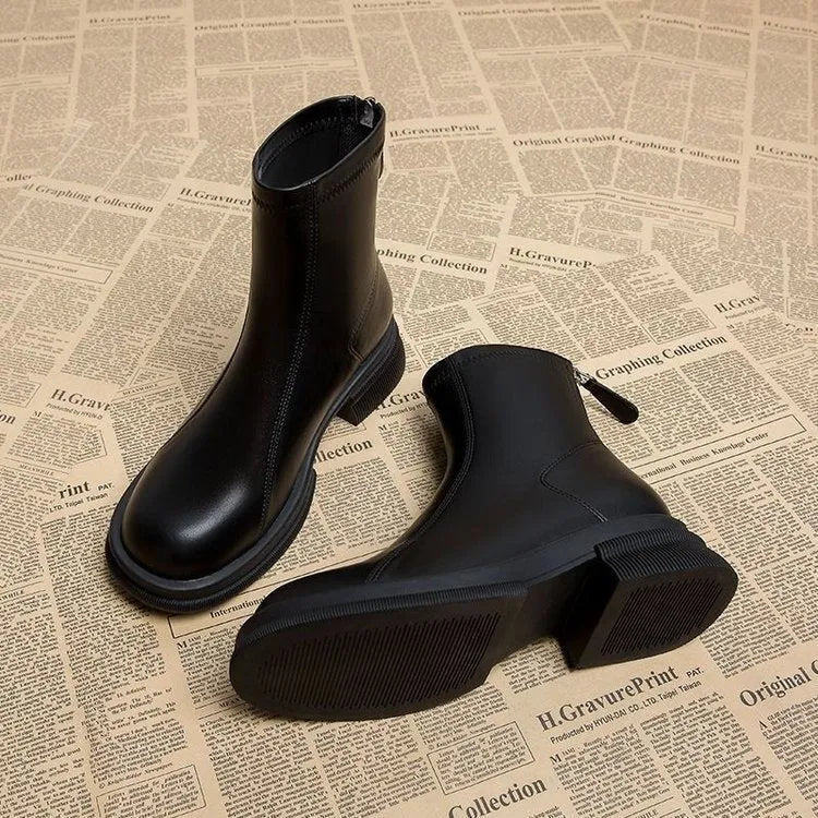 Women's black flat heel ankle boots with round toe and rear zipper on a rubber sole.