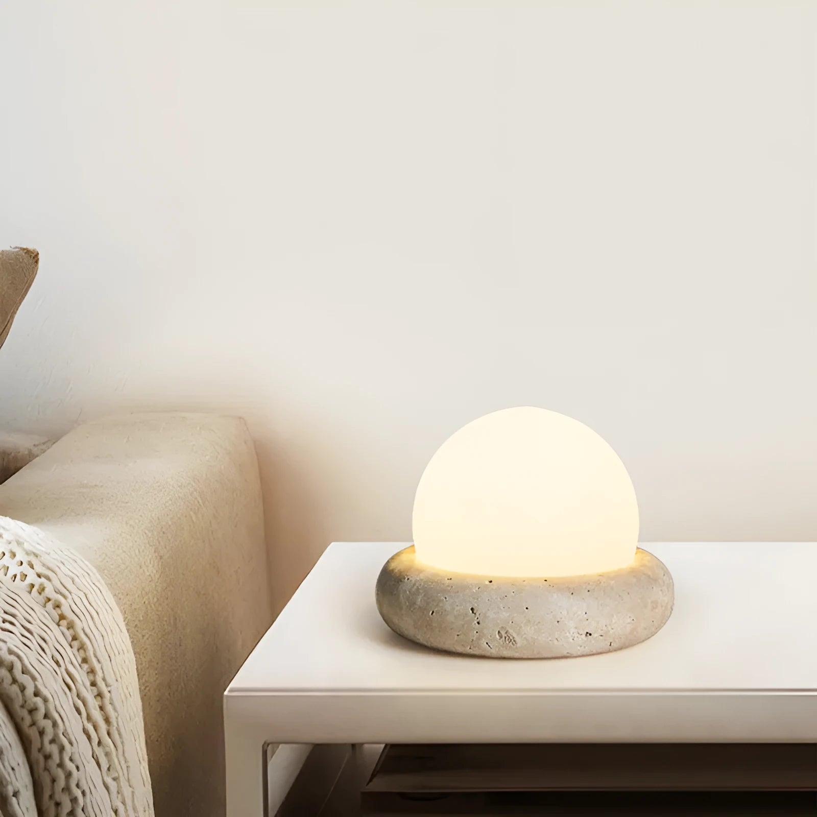 Cream coloured bedside night lamp with remote control on wooden table