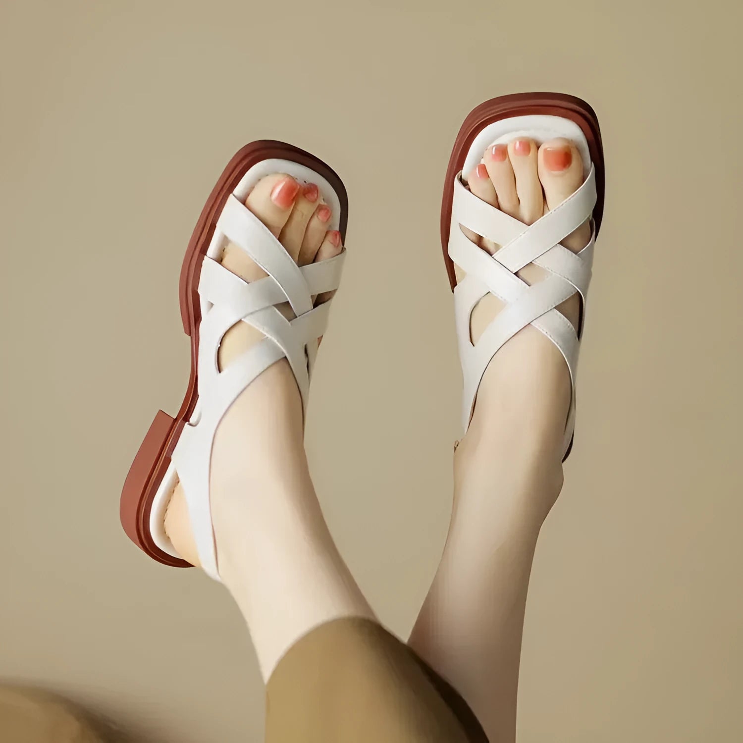 Women's glossy black patent leather sandals with a square toe and a cross-strap design on a low rubber sole.
