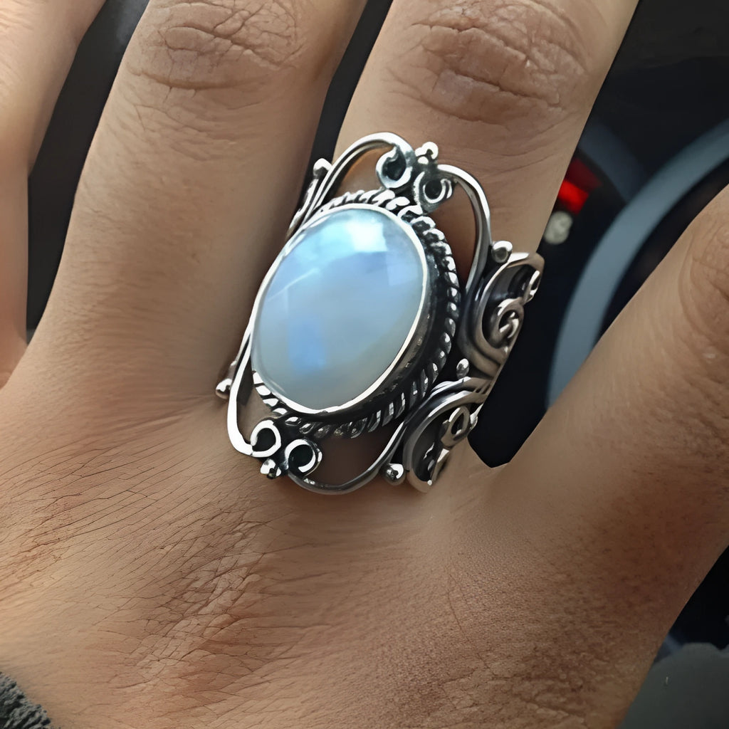 Vintage alloy ring with flower-shaped artificial moonstone gemstone on a neutral background showing side view