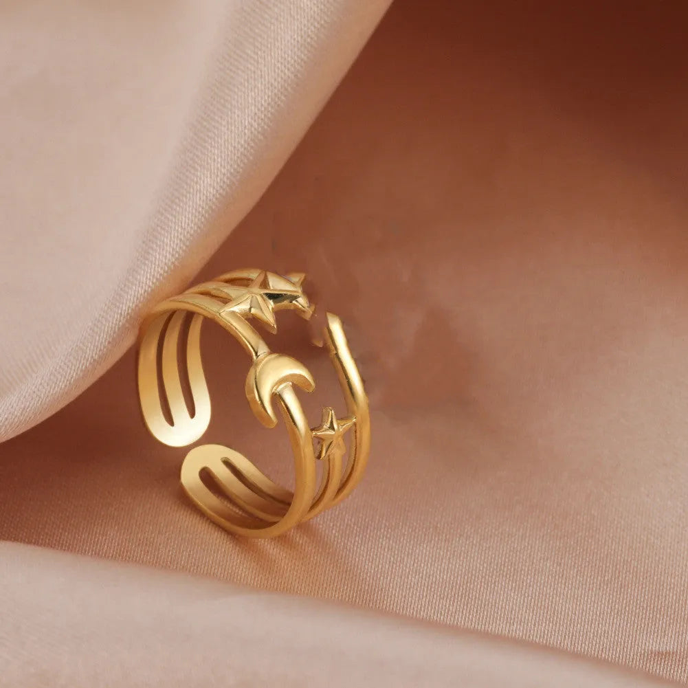 Gold electroplated stainless steel star shaped opening ring on a plain background