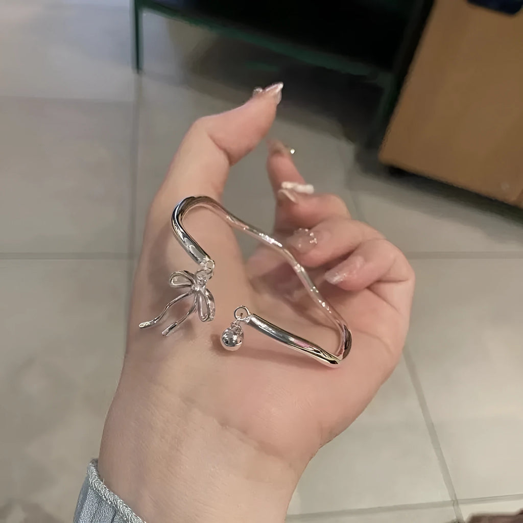 Silver adjustable bracelet with bow charm and bell opening mechanism