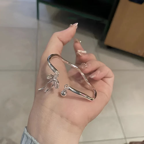 Silver adjustable bracelet with bow charm and bell opening mechanism