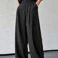 Man wearing black vertical striped pleated casual trousers with an elasticated waistband.