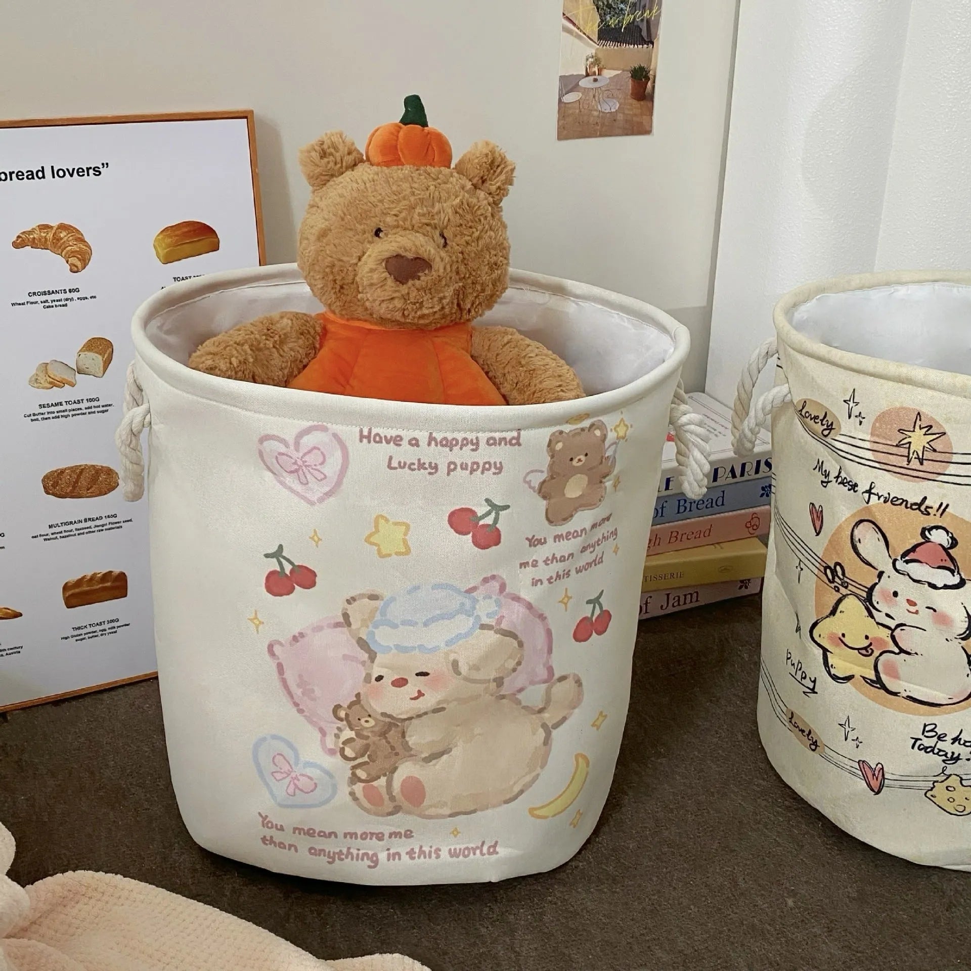Foldable cotton laundry basket featuring an illustrated design, shown in a bedroom setting.