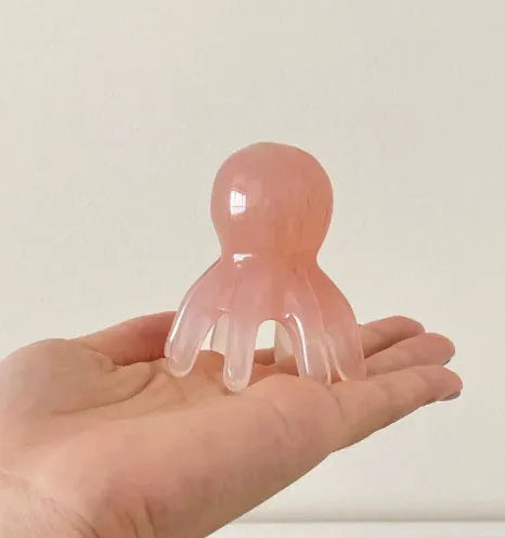 Pink natural resin octopus-shaped facial massage comb for periocular meridian therapy with storage bag.