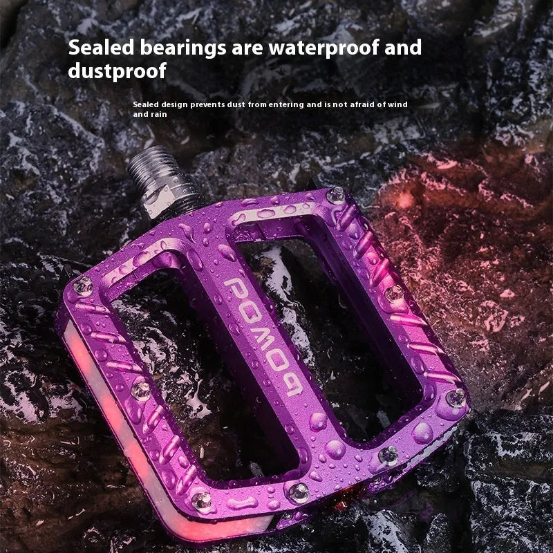 Aluminium alloy bicycle pedals with built-in 710LED lights in black, gold, purple, red, and titanium colour options.