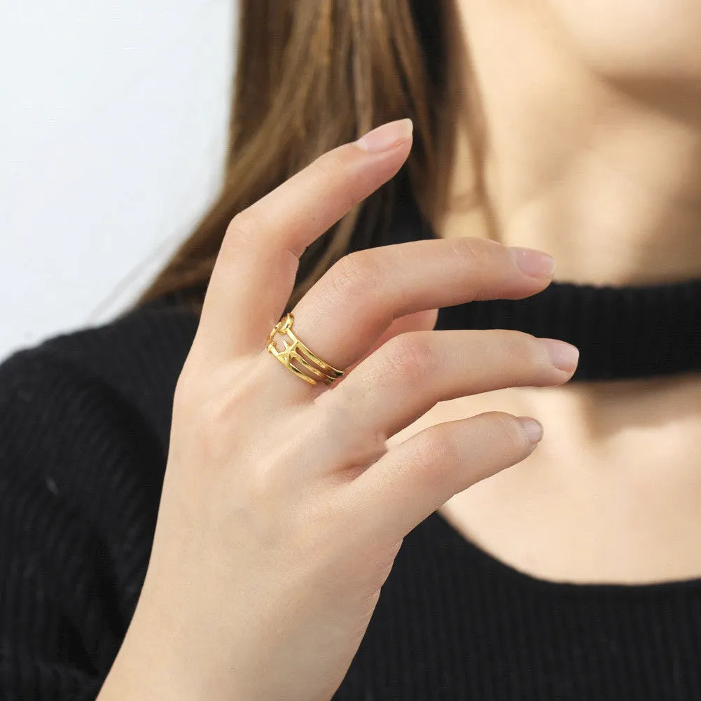 Gold electroplated stainless steel star shaped opening ring on a plain background