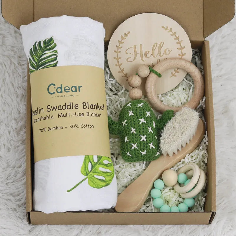 Baby teething toy gift set with bamboo blend gauze blanket, wooden beech bell, teether, brush, and milestone marker.