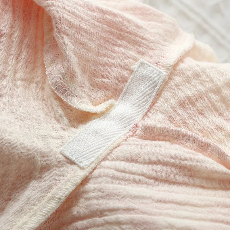 Women's pink cotton gauze lounge suit set with lace-up long sleeve top and matching trousers on a hanger.