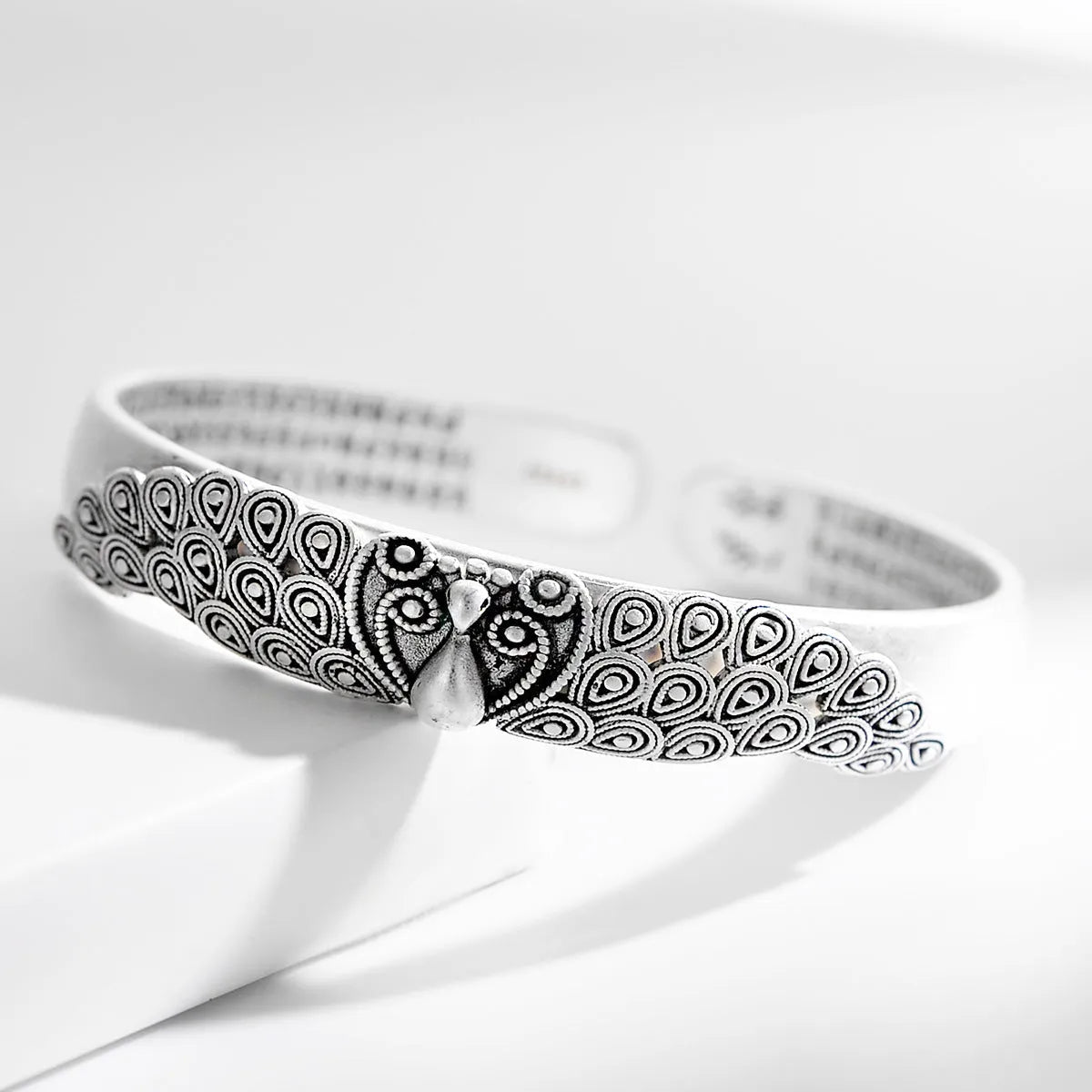 Antique copper plated silver bracelet with peacock open screen design on white background