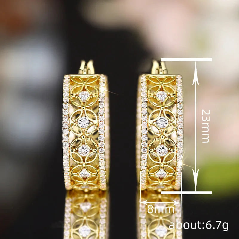 A pair of gold-coloured geometric butterfly earrings with floral details and horse eye styling on a white background.