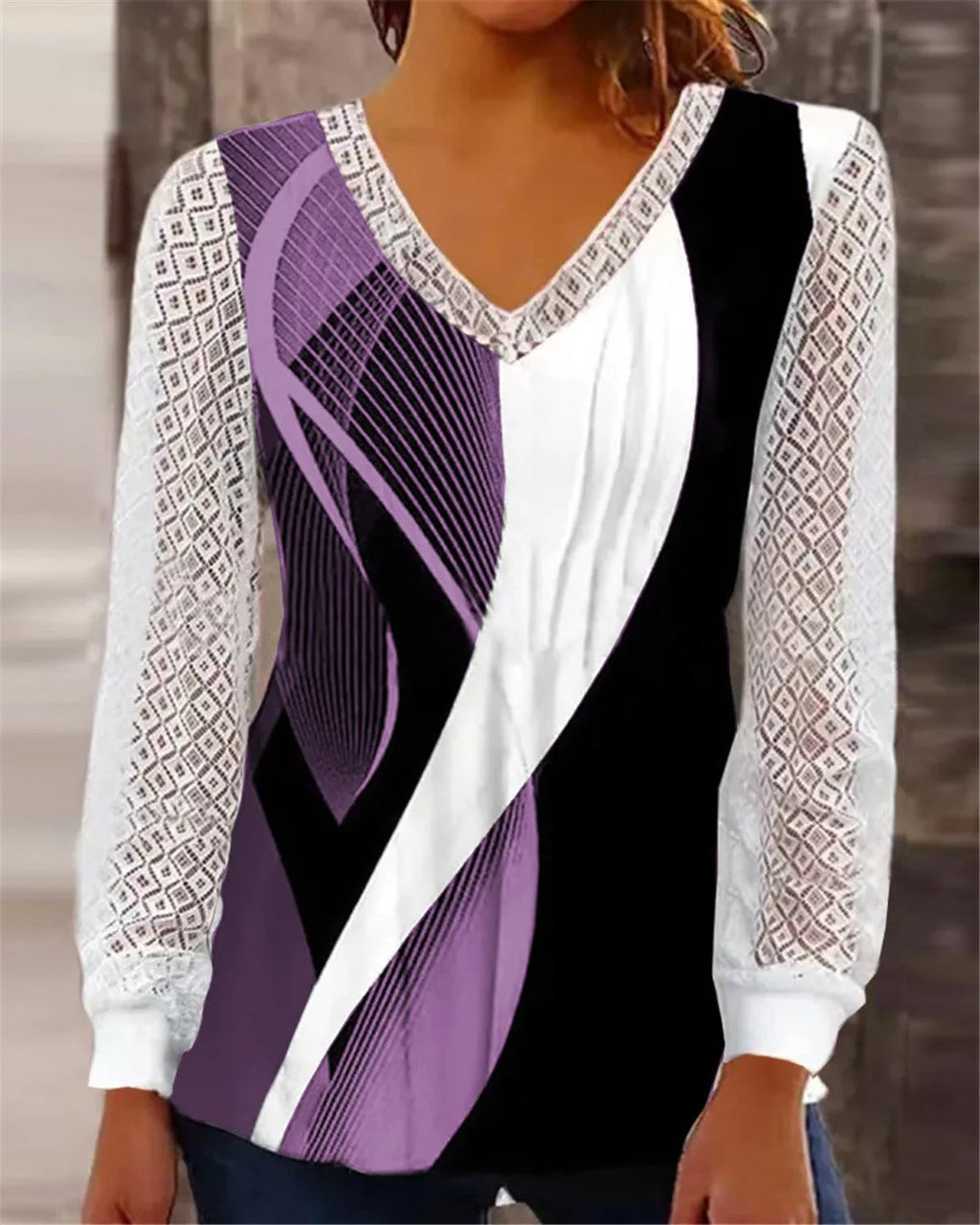 Purple loose V-neck top with lace print detail and long sleeves on a hanger.
