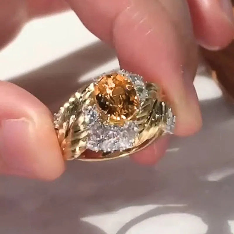 Gold women's ring with embossed feather pattern and a yellow zircon stone on a geometric copper band.