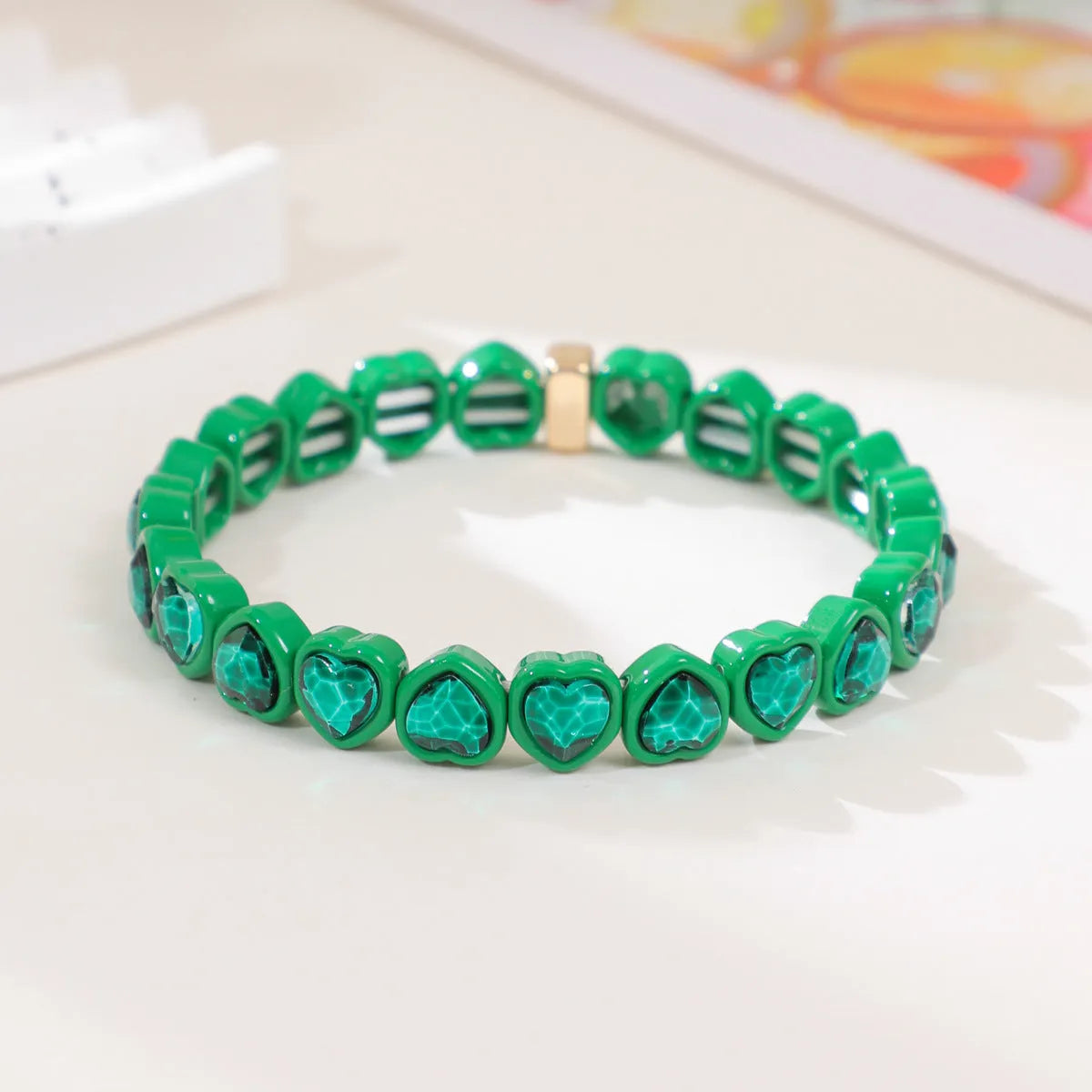Colourful enamel finish alloy heart charm on a black stretch bracelet band.