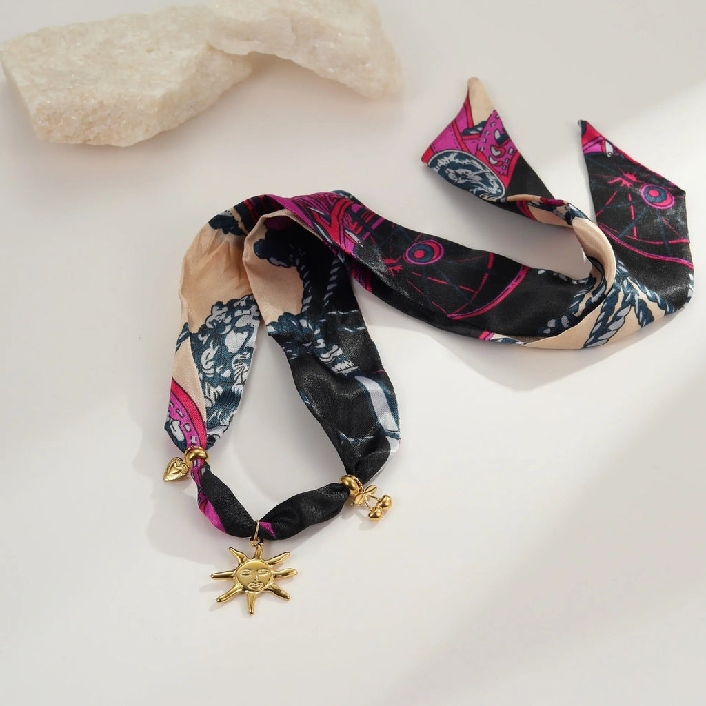 Geometric pendant on a gold chain, shown as a women's necklace or bracelet against an autumn backdrop.