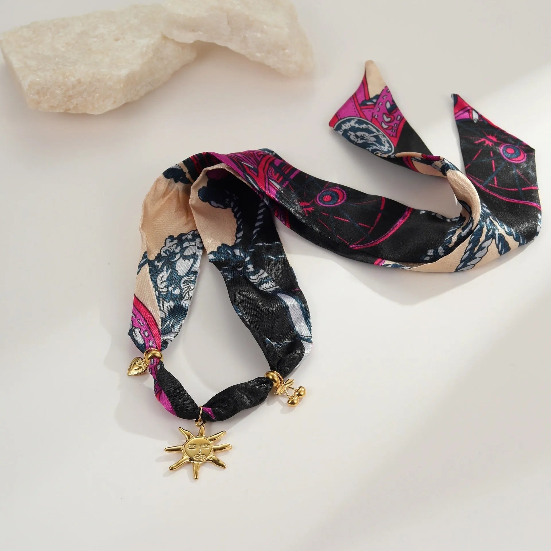 Geometric pendant on a gold chain, shown as a women's necklace or bracelet against an autumn backdrop.