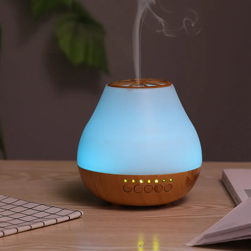 Wood grain finish USB aroma diffuser on a table next to a bottle of essential oil.