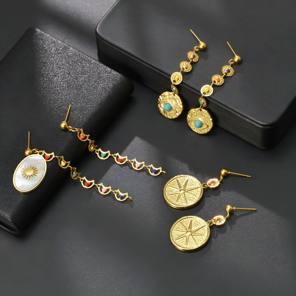 Three pairs of stainless steel geometry earrings: a star design, an eye design, and a shell sun design.