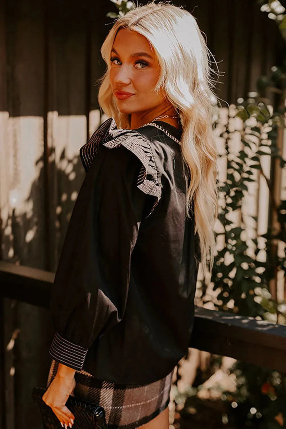 Black V-neck blouse with contrast stitching and ruffle long sleeves