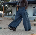 Men's grey wide-leg trousers with pleated waist and elastic waistband, shown on a model in a casual pose